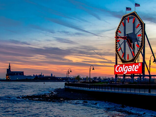 bord de mer, logo Colgate en arrière-plan sous une grande horloge aux aiguilles rouges