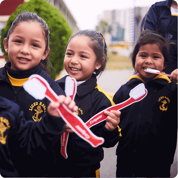 trois enfants souriants avec des brosses à dents factices.